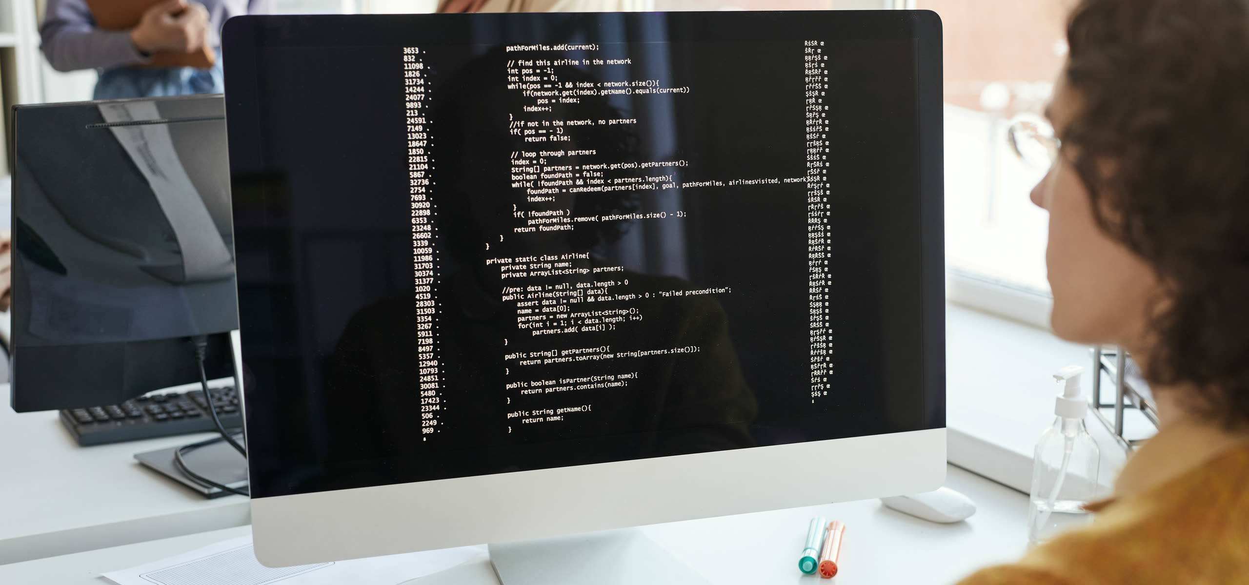 A developer at a desk, a database schema open on one screen and a half-built dashboard on the other
