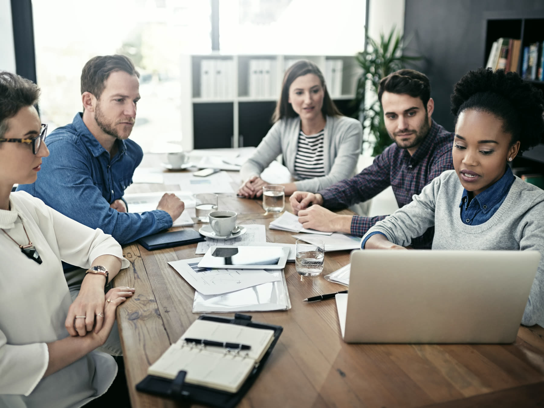 A working session around a table of laptops and printed notes